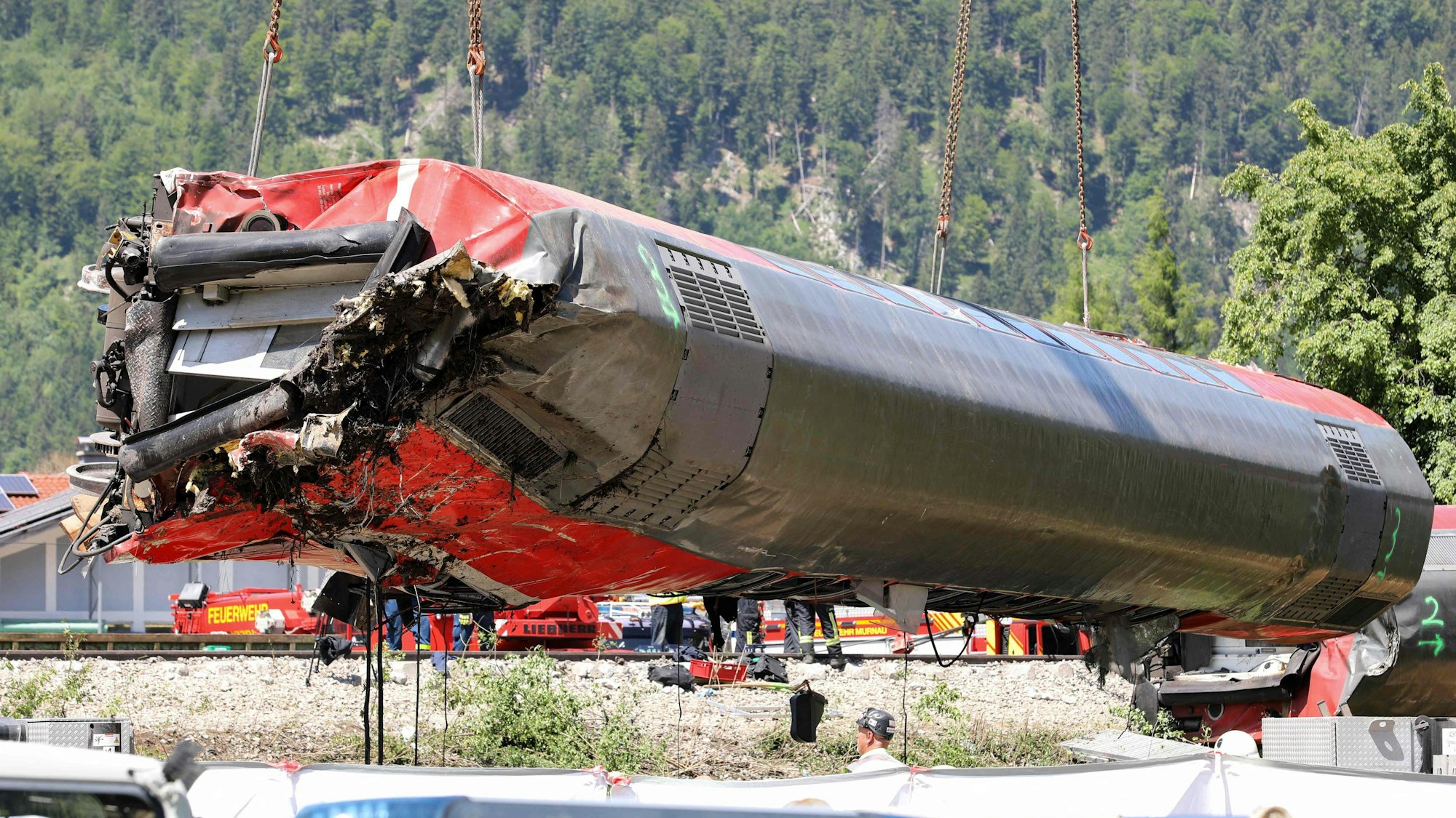 Arbeiter bergen am 4. Juni, einen Tag nach dem Unfall, den tonnenschweren Waggon am Unglücksort in Garmisch-Partenkirchen mit einem Kran. Die Identifizierung der fünf Todesopfer ist weitgehend abgeschlossen.