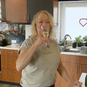 Friseurmeisterin Hiltrud steht bei „Das perfekte Dinner“ mit einem Glas Sekt in der Küche.