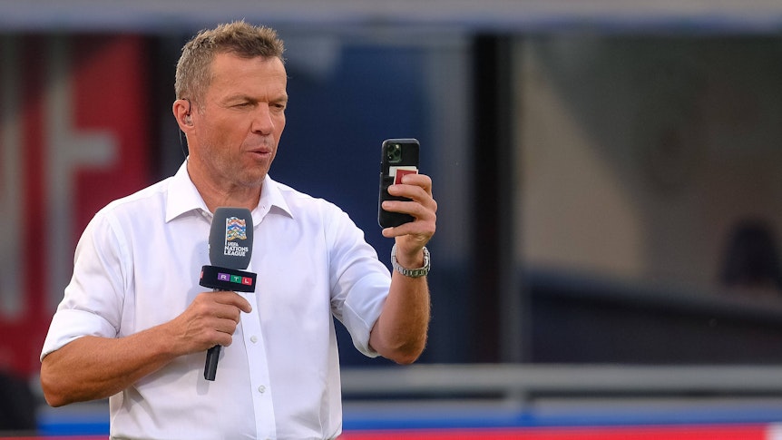 Ein Selfie muss sein! Weltmeister und TV-Experte Lothar Matthäus am 4. Juni 2022 in Bologna. Matthäus hält ein Smartphone in der linken Hand, in der rechten ein Mikrofon.