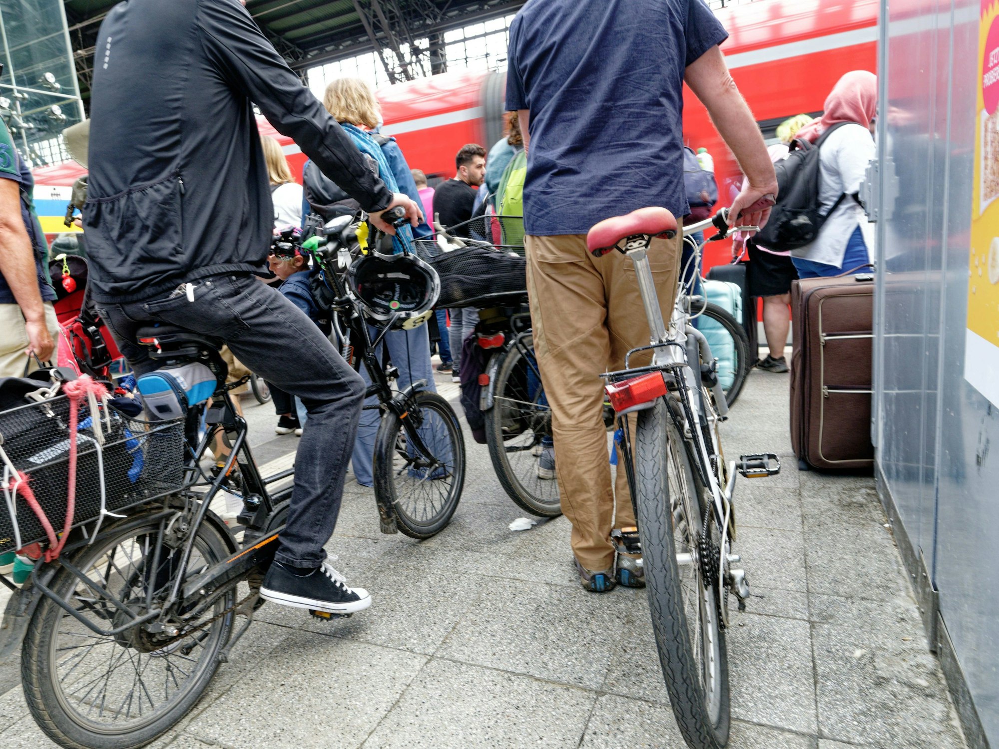 Reisende mit Fahrrädern auf einem Bahnsteig am Kölner Hauptbahnhof.