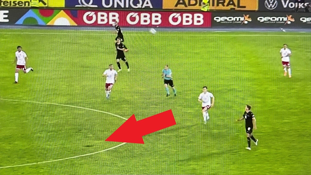 Ein roter Pfeil zeigt die Unebenheit auf dem Spielfeld.