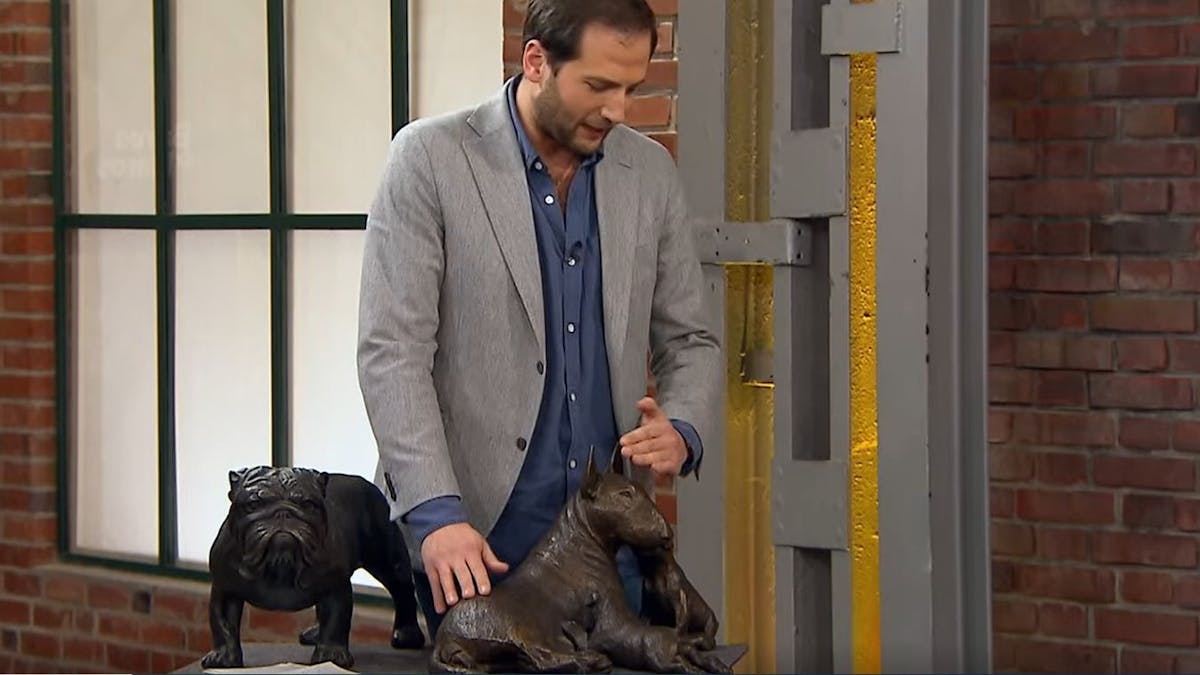 Händler Julian begutachtet zwei Hunde-Skulpturen