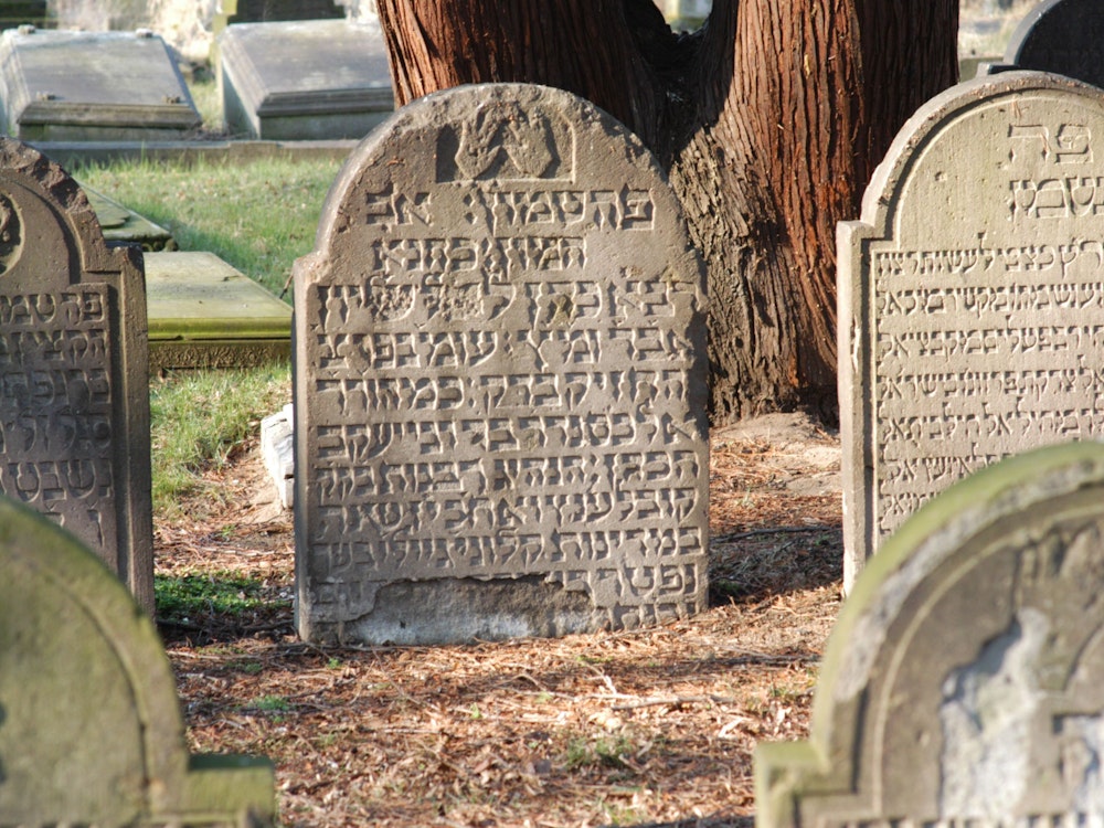 Grabsteine mit hebräischen Schriftzeichen stehen auf dem jüdischen Friedhof in Köln.