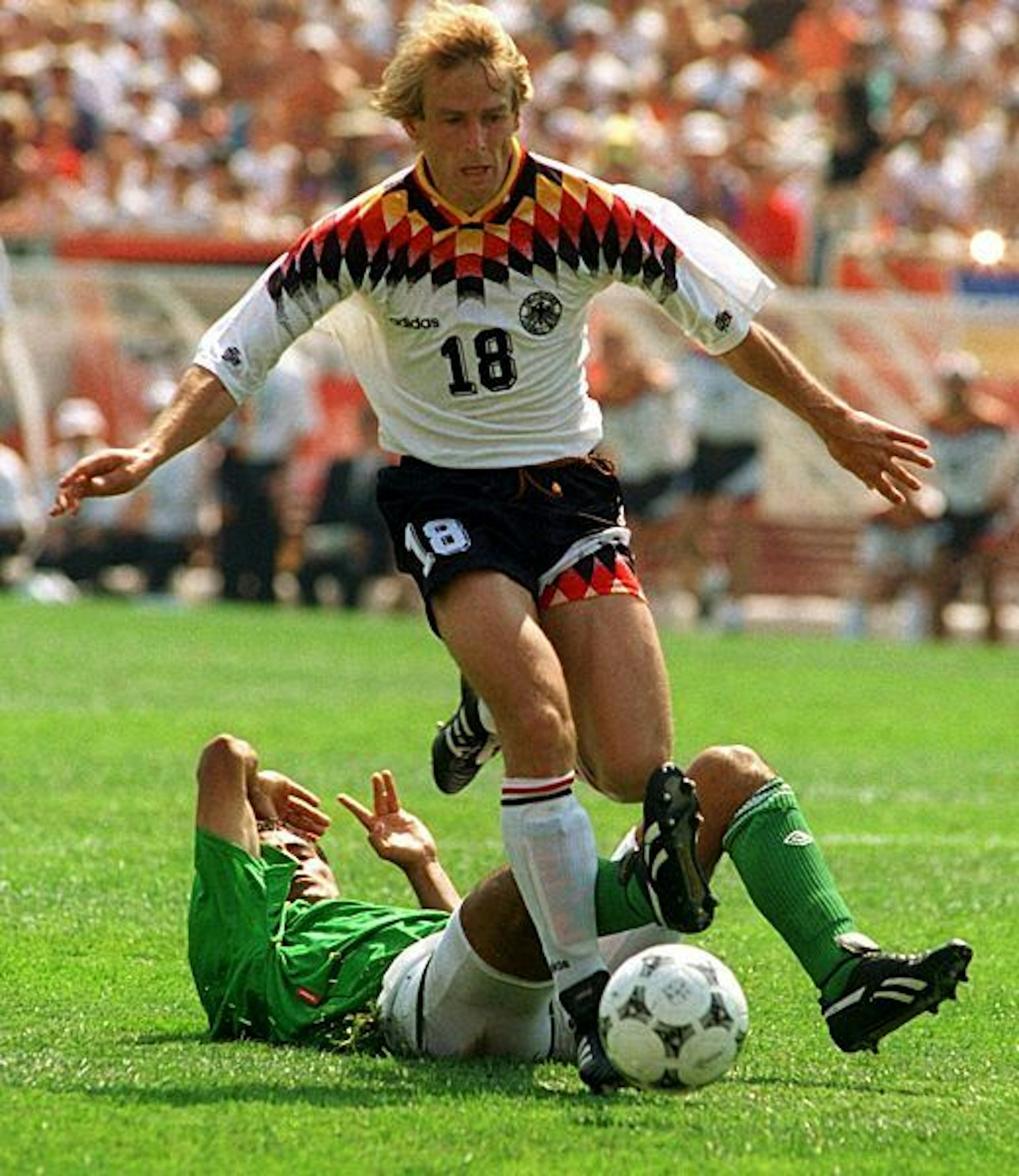 Jürgen Klinsmann dribbelt vor einem bolivischen Verteidiger, der grätschend auf dem Boden liegt