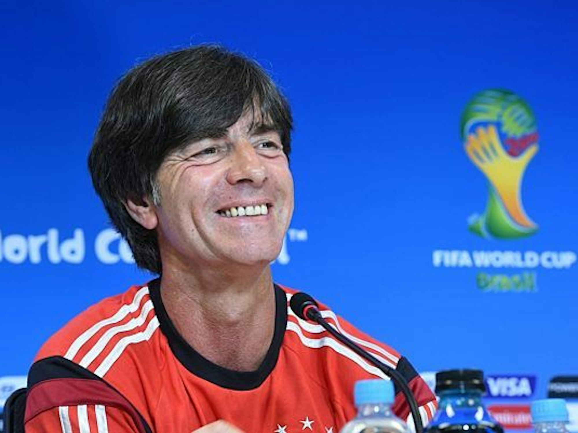 Löw hört lächelnd einem Journalisten bei einer Pressekonferenz bei der WM 2014 zu.