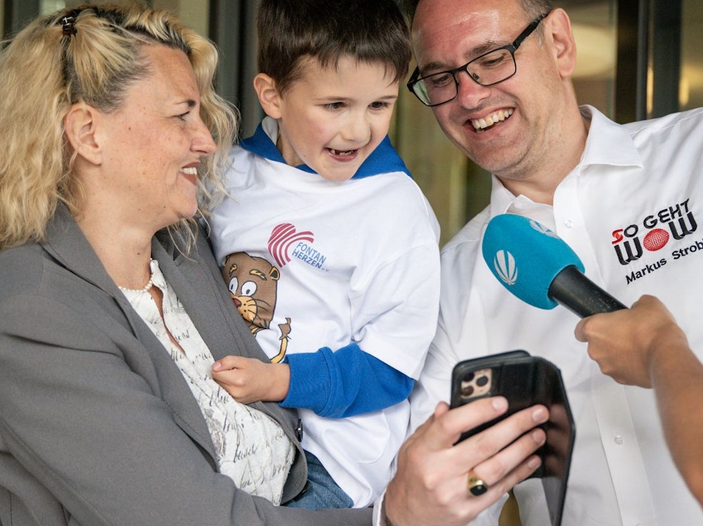 Ein kleiner Junge guckt auf das Handy von FrédARico-Erfinder Markus Strobl, der ihm den virtuellen Klinikclown vorführt.