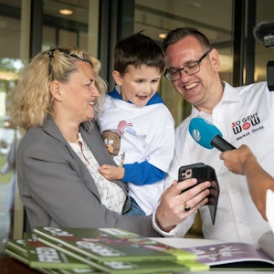 Ein kleiner Junge guckt auf das Handy von FrédARico-Erfinder Markus Strobl, der ihm den virtuellen Klinikclown vorführt.