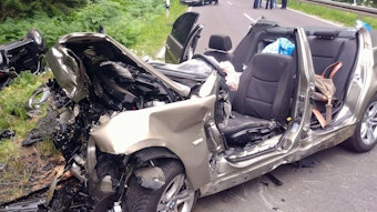 Zwei vollkommen zerstörte Autos liegen nach einem Unfall am Rand der Landstraße L12 zwischen Roetgen und Simmerath in der Eifel. Vier Personen wurden bei dem Zusammenstoß schwer verletzt, davon starb ein Kind später im Krankenhaus.