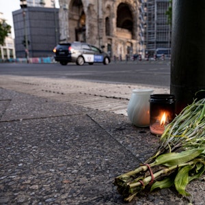 Kerzen und ein Blumenstrauß liegen auf dem Bürgersteig an der Tauentzienstraße in Berlin