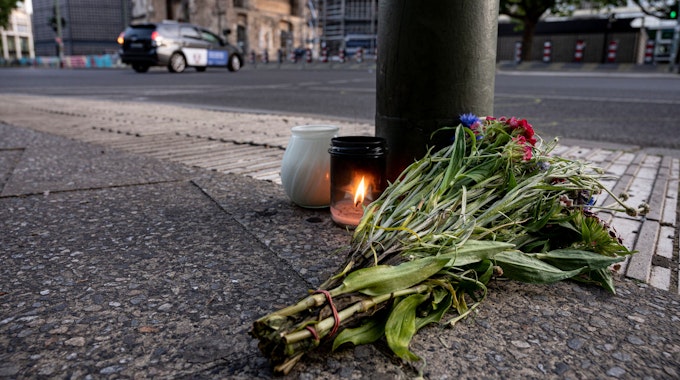 Kerzen und ein Blumenstrauß liegen auf dem Bürgersteig an der Tauentzienstraße in Berlin