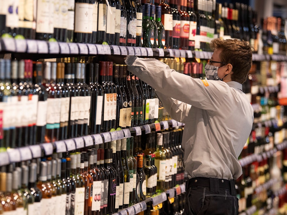 Beim Anblick dieser Flasche im Alkohol-Regal reagieren viele mit Fassungslosigkeit. Unser Foto zeigt einen Supermarkt-Mitarbeiter, der Waren in ein Regal einsortiert.