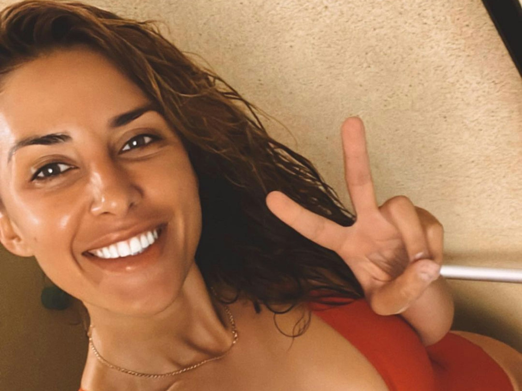 Victory-Zeichen und Badeanzug: Jana Azizi lacht in die Kamera beim Selfie.