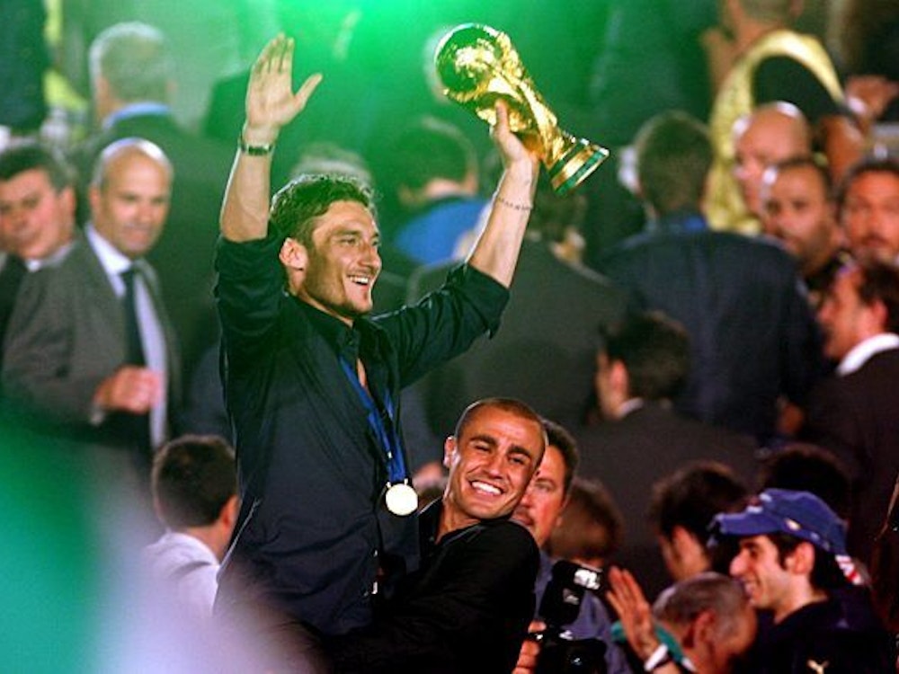 Cannavaro trägt Totti hoch, der den WM-Pokal hochstemmt.