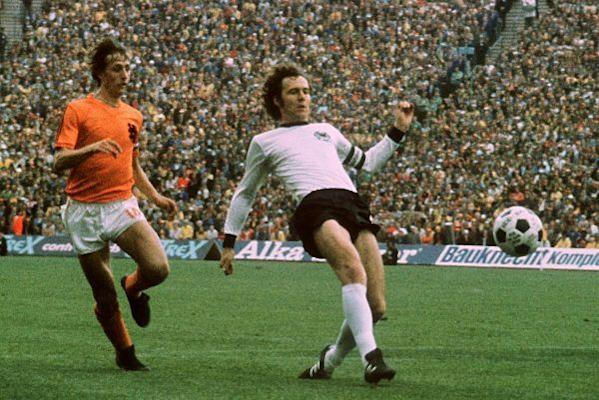 Franz Beckenbauer spitzelt den Ball vor Johan Cruyff weg.