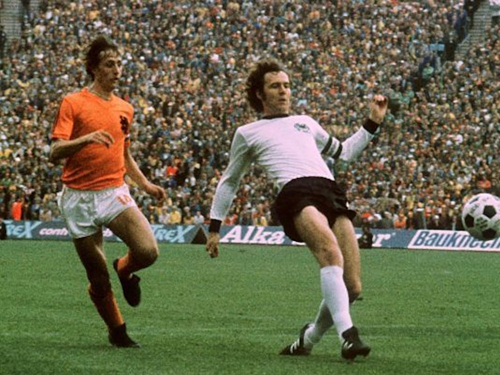 Franz Beckenbauer spitzelt den Ball vor Johan Cruyff weg.