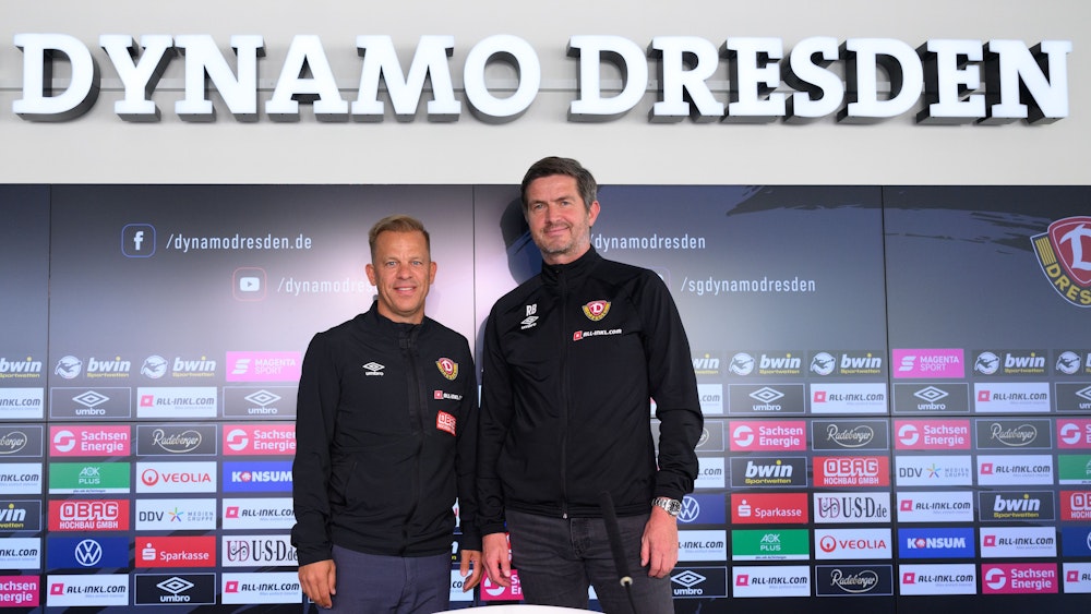 Markus Anfang (l), neuer Trainer des Drittligisten SG Dynamo Dresden, steht nach seiner Vorstellung in der AOK PLUS Walter-Fritzsch-Akademie auf dem Podium neben Ralf Becker.
