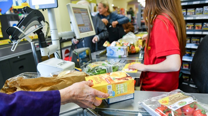 Die Kundinnen und Kunden müssen an der Kasse im Supermarkt immer tiefer in die Taschen greifen. Unser Foto zeigt eine Kassiererin, die Waren scannt.