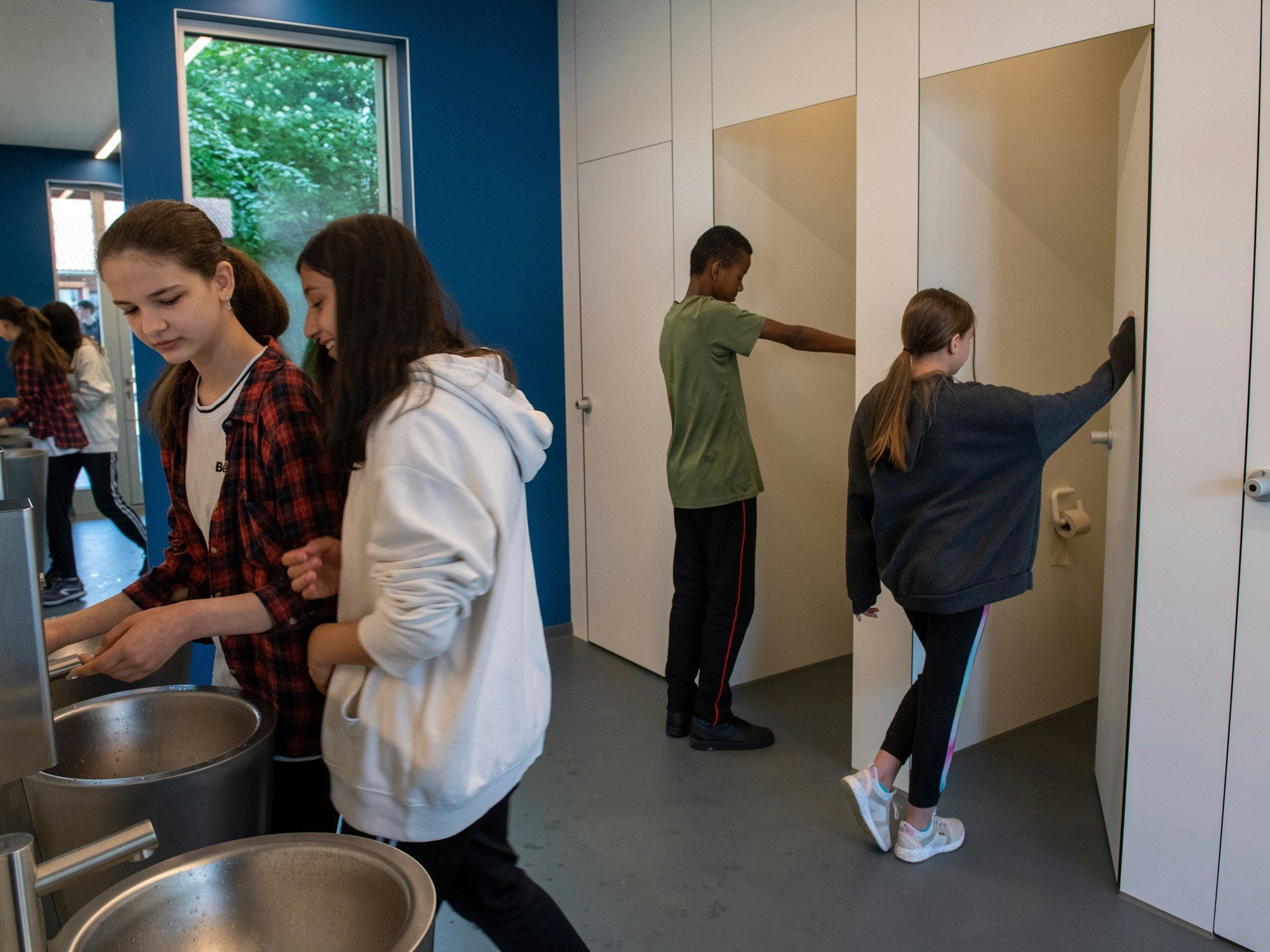 Jungen und Mädchen gehen in eine sogenannte Unisex-Toilette an der Sägefeldschule im Ortsteil Wiblingen (Baden-Württemberg).