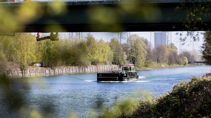 Ein Schiff fährt auf dem Rhein-Herne-Kanal unter einer Brücke hindurch.