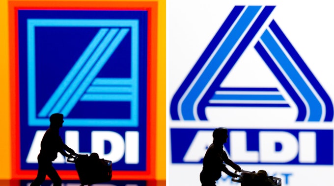 Eine kleine Plastikfigur mit einem Einkaufswagen in Berlin vor einem Logo von Aldi Süd (links) und Aldi Nord