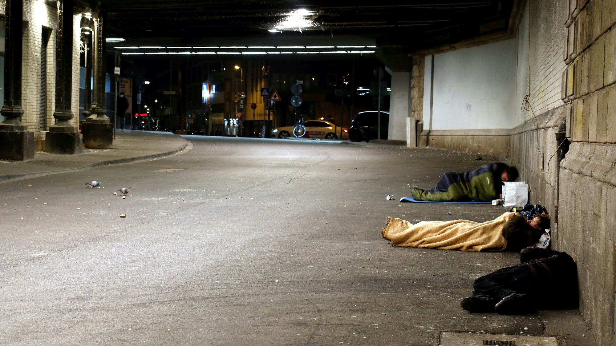 Obdachlose in Schlafsäcken in einer Unterführung.