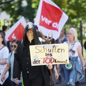 Mitarbeiterinnen und Mitarbeiter der Uniklinik laufen während einer Demonstration am 14. Juni 2022 mit einem Transparent mit der Aufschrift „Schuften bis der Tod kommt“ durch Bonn.