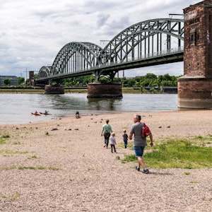 Menschen gehen am Rhein spazieren, die Sonne scheint.
