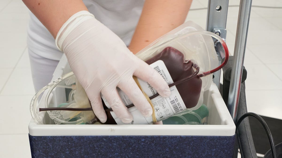 Ein Mitarbeiter des DRK-Blutspendedienstes verstaut eine Blutkonserve in einem Kühlbehälter.