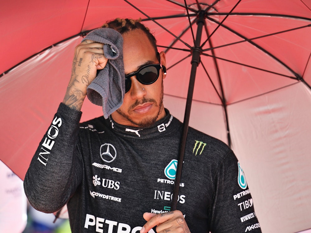 Lewis Hamilton aus Großbritannien vom Team Mercedes wischt sich vor dem Rennen unter einem Sonnenschirm den Schweiß mit einem Handtuch vom Gesicht.