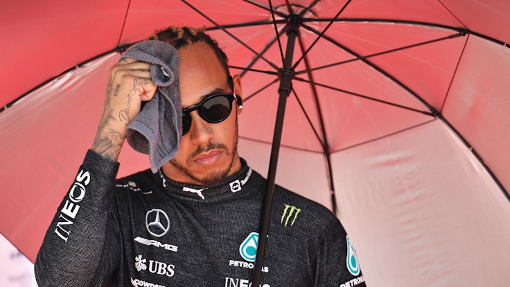 Lewis Hamilton aus Großbritannien vom Team Mercedes wischt sich vor dem Rennen unter einem Sonnenschirm den Schweiß mit einem Handtuch vom Gesicht.