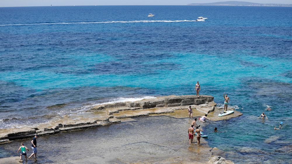 Menschen entspannen sich am Felsenstrand von Maioris an der Südostküste Mallorcas.