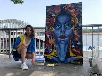 Die 28-jährige Ukrainerin Vika gemeinsam mit ihrem Kunstwerk am Rheinufer in Köln.