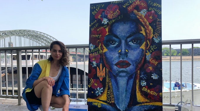 Die 28-jährige Ukrainerin Vika gemeinsam mit ihrem Kunstwerk am Rheinufer in Köln.