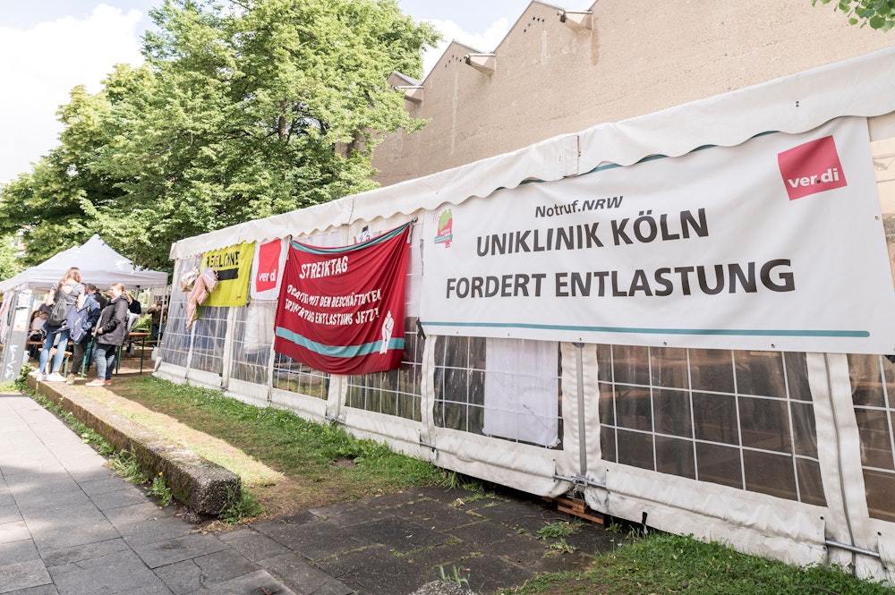 Streik an der Uniklinik in Köln, zu sehen ist ein Plakat auf einem Pavillon.