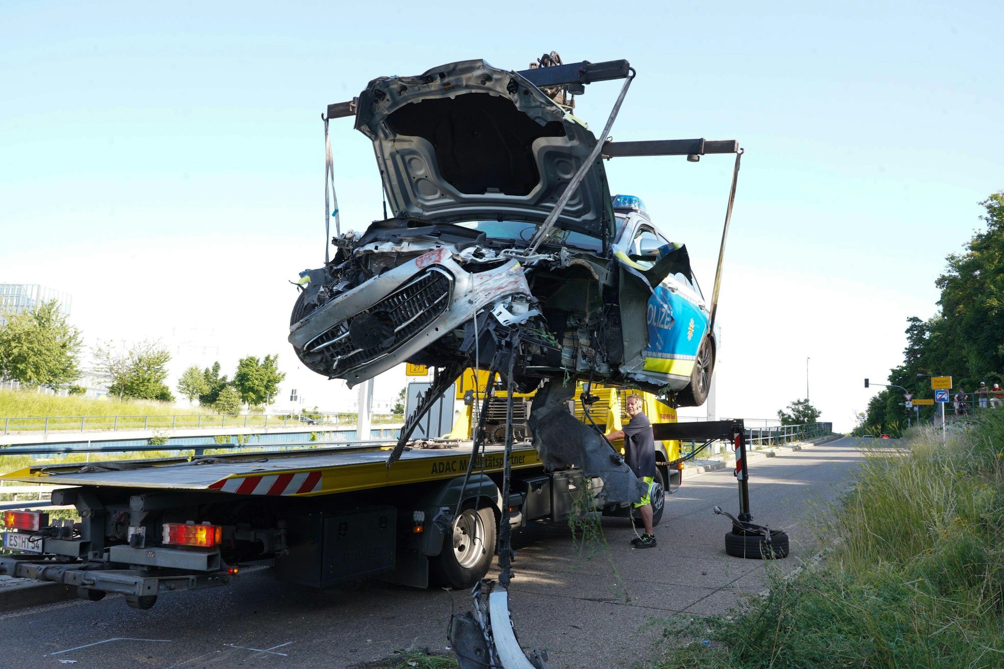 21.06.2022, Baden-Württemberg, Stuttgart: Ein Abschleppwagen hebt das kaputte Polizeiauto auf die Ladefläche nach einer Verfolgungsjagd.