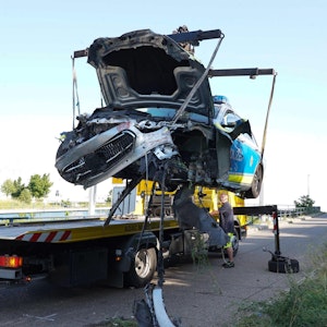 21.06.2022, Baden-Württemberg, Stuttgart: Ein Abschleppwagen hebt das kaputte Polizeiauto auf die Ladefläche nach einer Verfolgungsjagd.