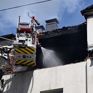 Feuerwehrleute löschen einen Brand in einem Dachstuhl. In einem Mehrfamilienhaus in Leverkusen hat es am Freitagmorgen eine Explosion gegeben.