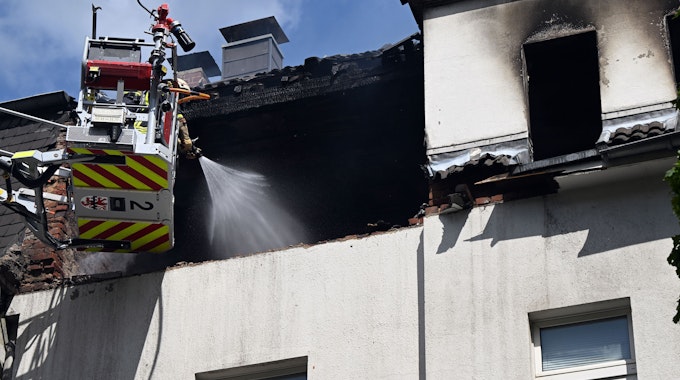 Feuerwehrleute löschen einen Brand in einem Dachstuhl. In einem Mehrfamilienhaus in Leverkusen hat es am Freitagmorgen eine Explosion gegeben.