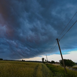 Am späten Abend zieht eine Gewitterzelle mit dunklen Regenwolken über die Landschaft.