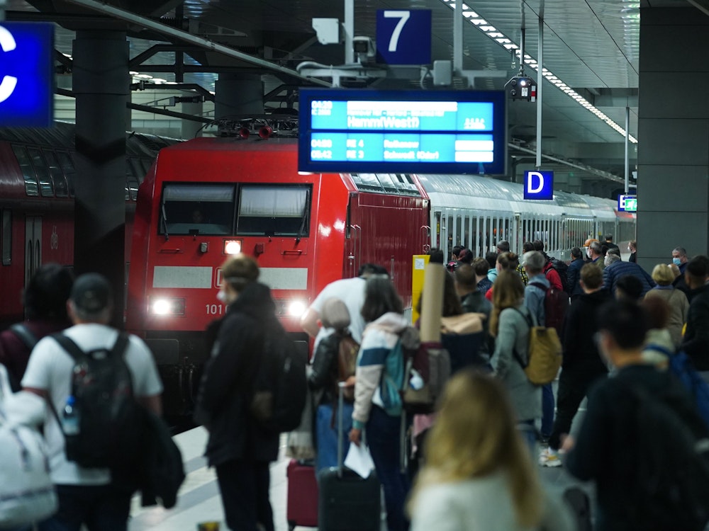 Reisende warten im Hauptbahnhof Berlin auf die Einfahrt eines Intercity.