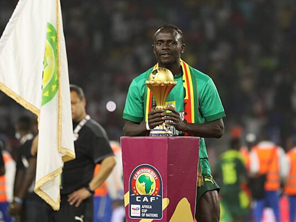 Sadio Mané stellt sich mit dem Afrika Cup-Pokal für ein Siegerfoto auf.