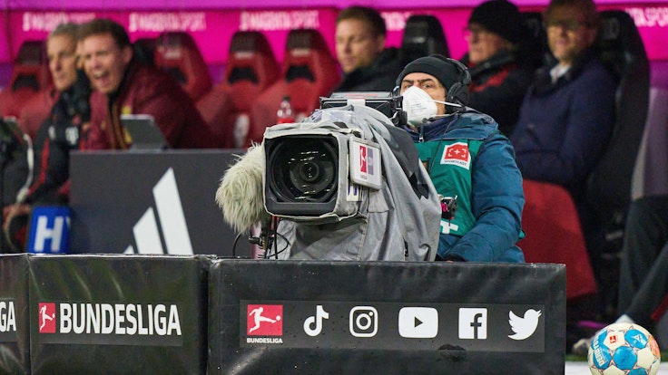 Ein Kameramann sitzt beim Bundesliga-Spiel gegen RB Leipzig vor der Bank des FC Bayern München