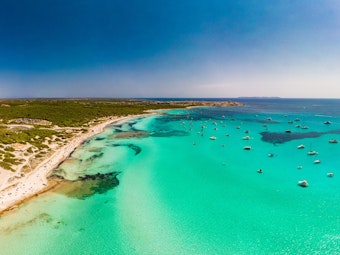 Eine Drohnenaufnahme der Playa Es Trenc auf Mallorca mit dem weißen Sand und türkisfarbenem Meer.