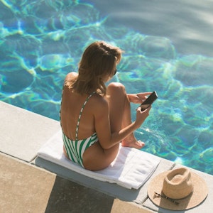 Getty Images: Eine Frau sitzt auf dieser undatierten Aufnahme am Pool und checkt ihr Handy.