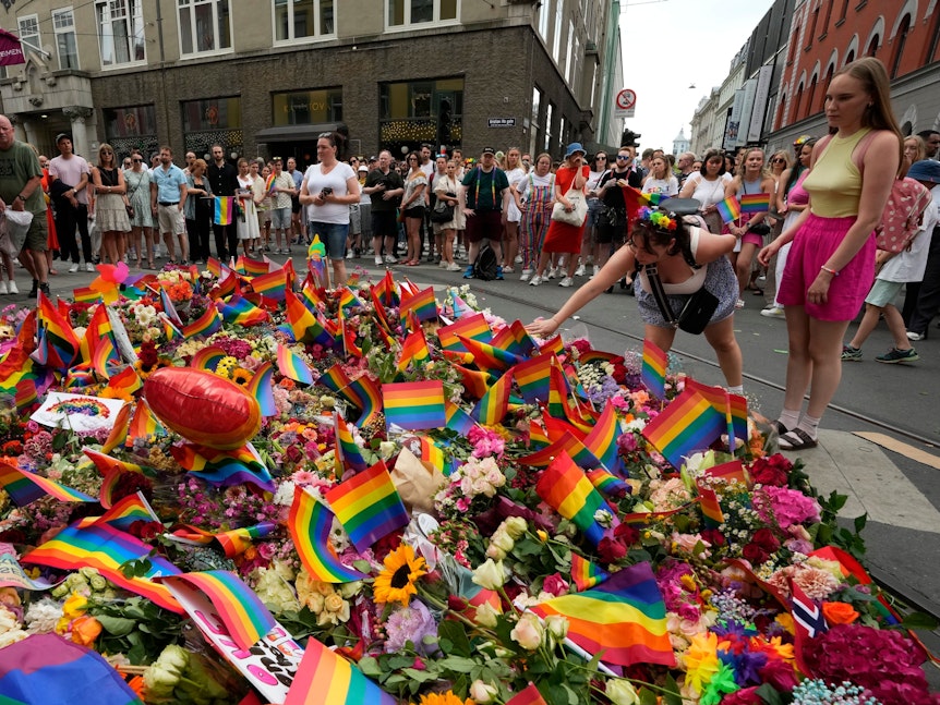 Menschen legen am Samstag, 25. Juni 2022, am Ort der Schießerei im Zentrum von Oslo Blumen nieder. Ein Schütze eröffnete am frühen Samstag das Feuer im Ausgehviertel von Oslo und tötete zwei Menschen.