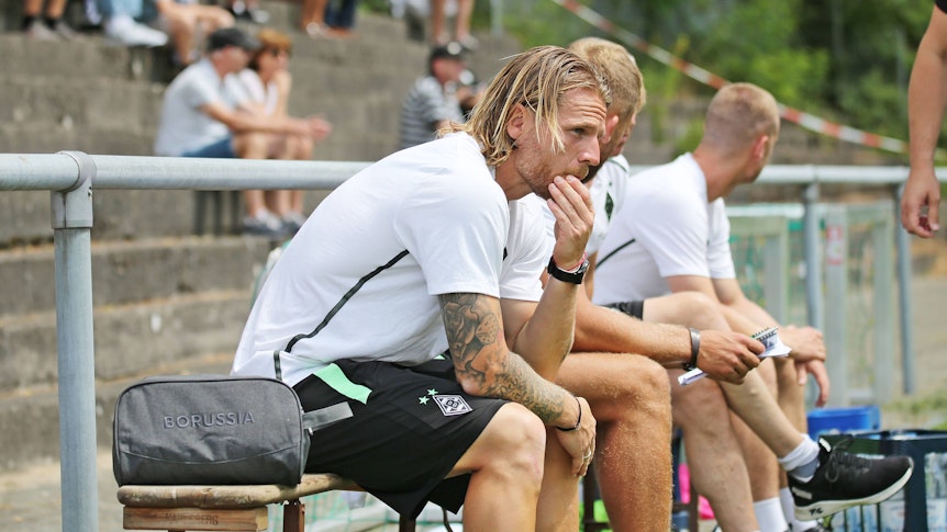 Eugen Polanski am 25. Juni 2022 als Trainer der U23 von Borussia Mönchengladbach gegen SV Elversberg. Polanski sitzt au einer Bank und stützt das Kinn auf den Armen auf.