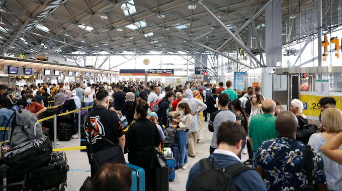 Passagiere stehen in einer Schlange von mehreren hundert Metern für die Sicherheitskontrolle am Flughafen Köln-Bonn an