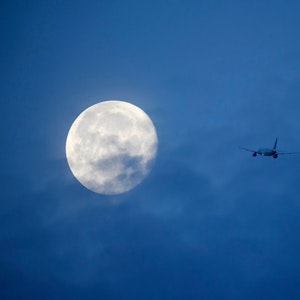 Der Mond ist hinter einem Flugzeug zu sehen