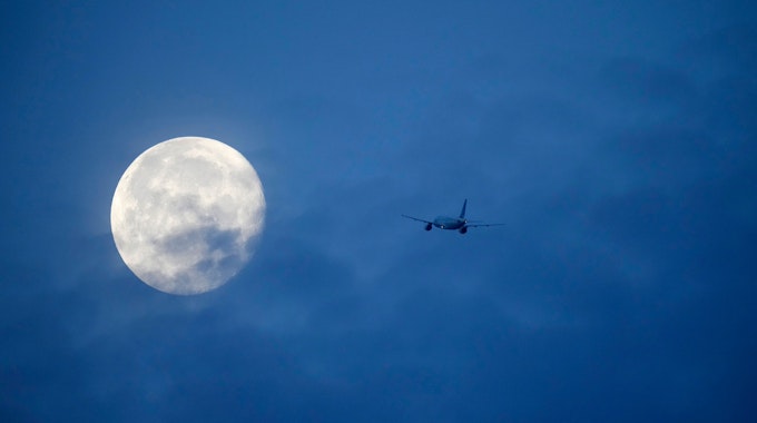 Der Mond ist hinter einem Flugzeug zu sehen