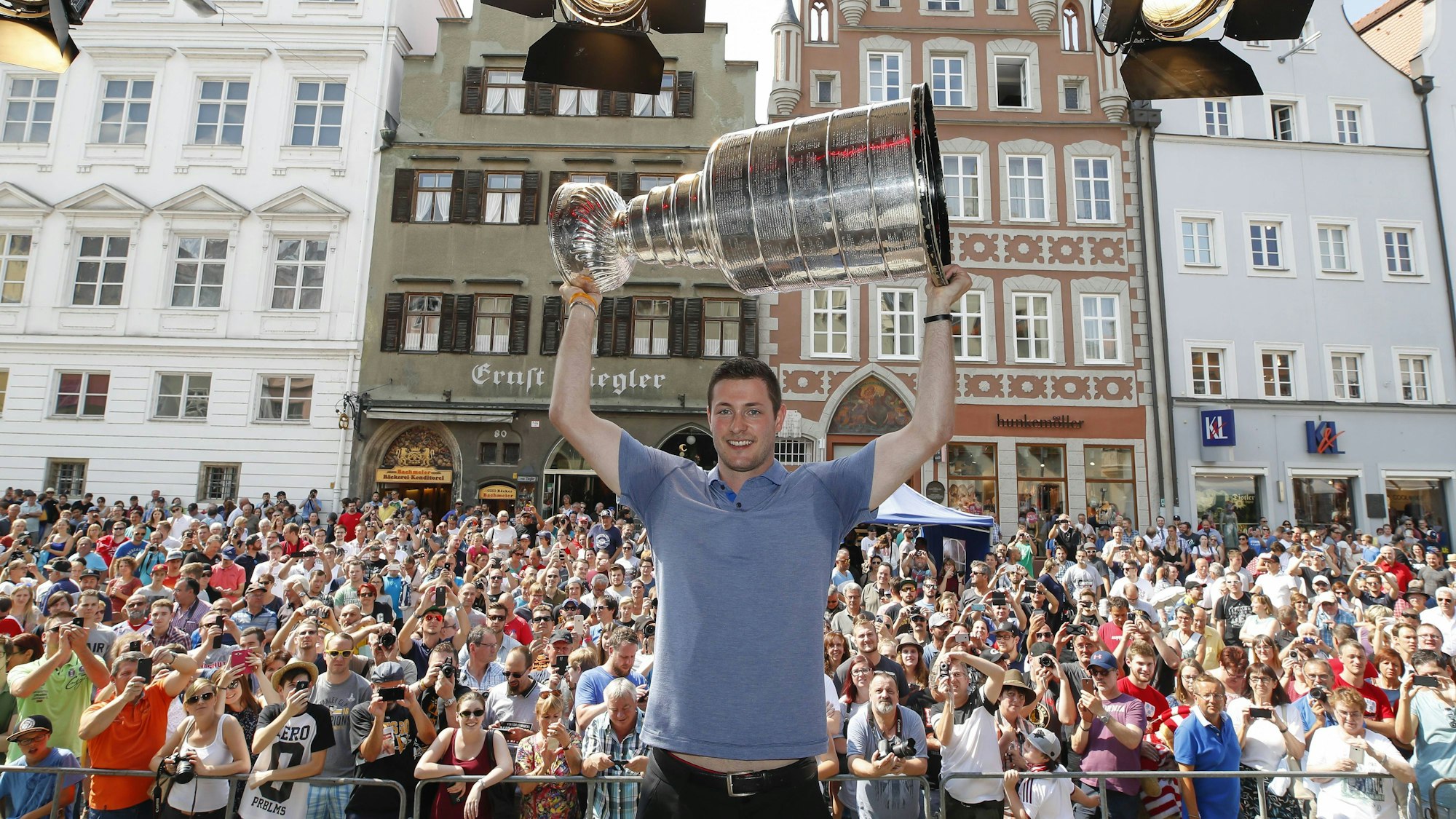 Der deutsche Eishockey-Profi Tom Kühnhackl hält vor einem großen Publikum in Landshut die Stanley-Cup-Trophäe in die Luft.